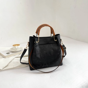 Black litchi grain tote bag with embossed lettering and brown cylindrical handles