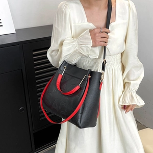 Fashionable black embossed leather bucket bag with red handles and gold hardware