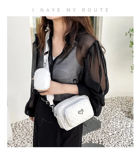 Close-up of white quilted PU crossbody bag with silver heart buckle and round coin purse
