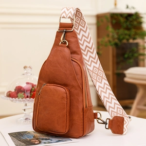 Vintage brown leather crossbody sling bag with ethnic style strap on white table