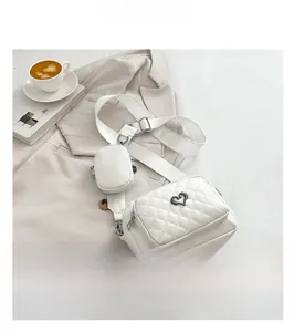 White quilted faux leather crossbody bag set with heart buckle on a beige blazer