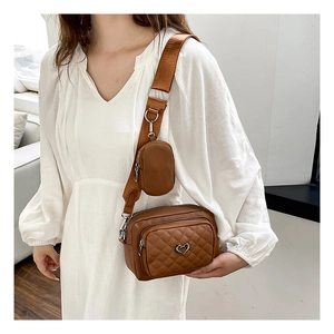 Close-up of brown quilted faux leather crossbody bag with silver heart logo and round pouch