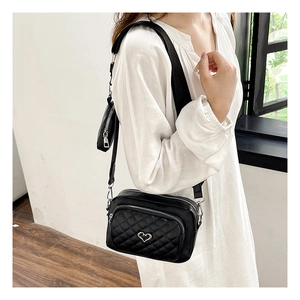 Close-up of black quilted PU leather crossbody bag with silver heart charm and pouch