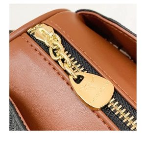Detailed macro of golden metal zipper and brand logo on brown leather handbag