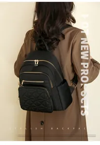 Detail of black quilted nylon backpack featuring golden zippers and multi-pocket structure