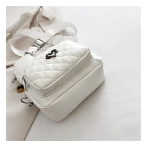 Close-up of quilted cream crossbody bag with black heart buckle and mini coin pouch