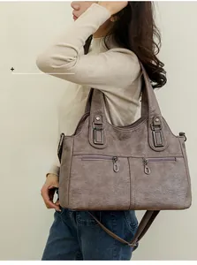 Detail of greyish-brown tote bag with dual front zippers and pleated textured synthetic leather