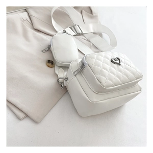 Detail of white quilted crossbody bag with heart buckle and detachable small coin purse