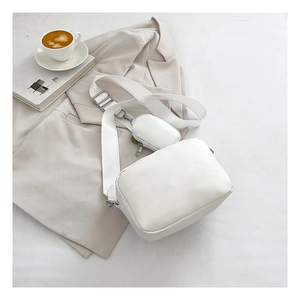 Detailed view of white minimalist PU crossbody bag with wide strap and coin purse attachment