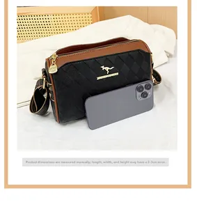 Close-up of quilted leather crossbody bag with golden logo and patterned strap next to a phone