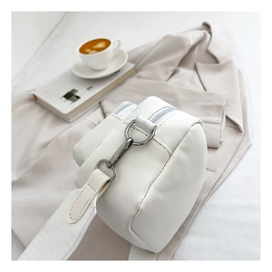 Detail of white PU leather crossbody bag with silver hardware and wide fabric shoulder strap
