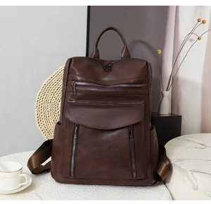 Macro detail of brown vintage PU leather backpack with multiple zip pockets and metal hardware