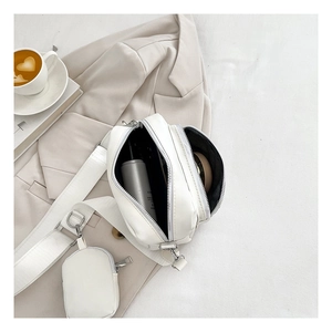Detail of white PU leather crossbody bag with dual zippers and detachable mini pouch