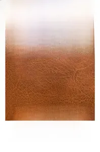 Detailed macro view of brown lychee-textured PU leather fabric for durable backpack material