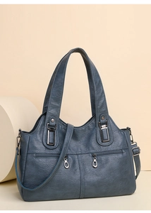 Close-up of a blue soft faux leather tote bag with silver zippers and a long shoulder strap