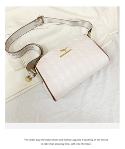 Detail of white quilted crossbody bag with golden logo and wide fabric strap