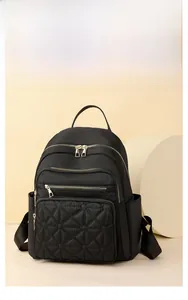 Detail of black quilted nylon backpack with gold-tone zippers and top handle