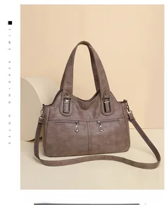 Close-up of taupe litchi grain faux leather bag with metal zipper details and strap