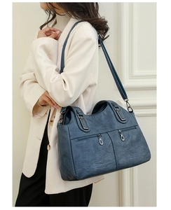 Detail of vintage blue tote bag showing oily wax leather texture and dual front zip pockets