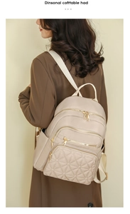Detail of beige quilted backpack on model with gold zippers and spacious side pockets