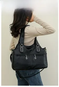 Detail of black pebbled faux leather tote bag with silver vertical zipper pockets