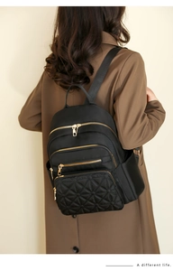 Detailed view of quilted black nylon backpack featuring premium gold-tone metal zippers