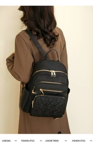 Detail of black quilted nylon backpack with gold zippers for urban daily commuting