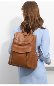 Brown litchi grain leather backpack on model, featuring front flap and side pockets