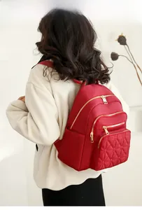 Detail view of a large red nylon backpack with diamond quilting and gold zippers
