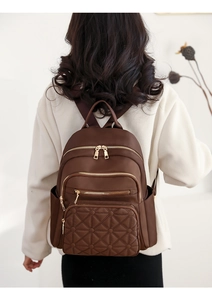 Detailed back view of a brown quilted backpack with gold zippers for daily commuting