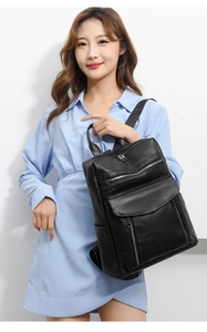 Detail of black pebbled leather backpack showing multi-pocket design on model