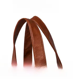 Detail view of reinforced stitching on the brown soft leather handles of a tote bag