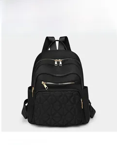 Detailed view of black nylon backpack featuring diamond-quilted pocket and gold zippers