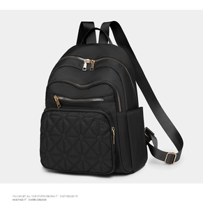 Detail of black backpack showing diamond quilted embroidery and gold hardware zippers