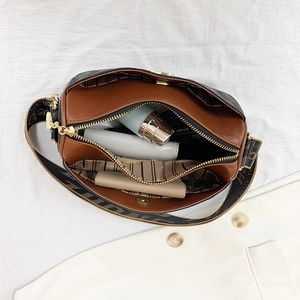 Brown quilted cylinder pillow bag with wide strap showing spacious inner storage space