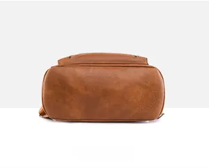 Detail view of the brown leather backpack bottom featuring neat stitching and pebble texture