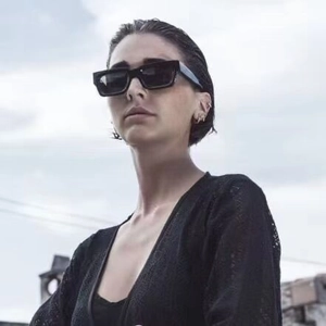 Close-up of stylish black rectangular sunglasses on a model with an outdoor sky background