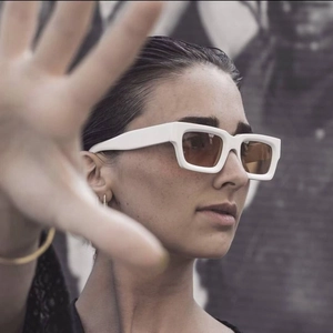 Close-up of stylish thick-framed white sunglasses with translucent brown lenses on model