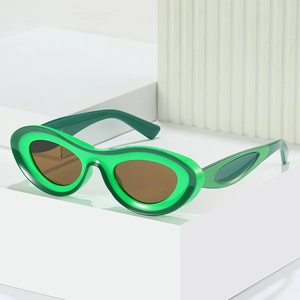 Vintage oval sunglasses with contrast green frames and brown lenses on white blocks