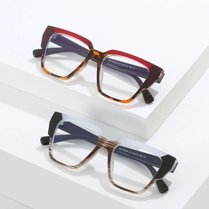 Square TR90 optical frames in gradient red and striped grey on a geometric white stand