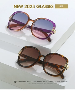 Detailed macro view of trendy oval sunglasses featuring golden metal hinges and gradient lenses