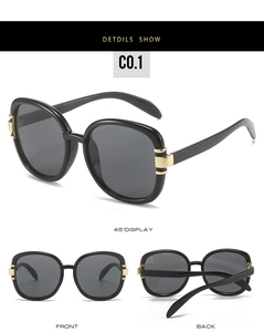 Detail view of oval sunglasses with black frames and decorative gold metal rings on temples