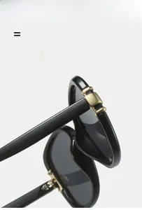 Detail of high-elasticity hinge on black oval sunglasses with golden metal accents