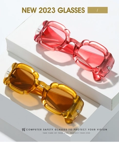 Détail des lunettes de soleil Y2K aux montures ondulées en résine rouge et ambre