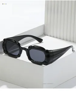 Détail de lunettes de soleil Y2K noires avec monture ondulée sur support géométrique