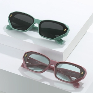 Modern thick geometric sunglasses with mint green and pink frames featuring gold rivets