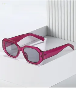 Detail of pink transparent hexagonal sunglasses featuring silver rivet accents on the frame