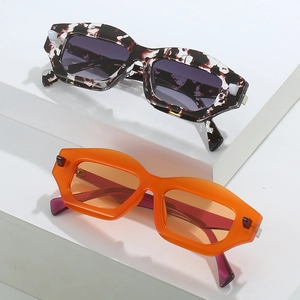 Fashionable geometric sunglasses in tortoiseshell and translucent orange frames on white stand