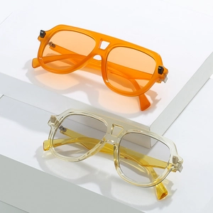 Lunettes de soleil aviateur rétro à monture épaisse orange et jaune sur support moderne