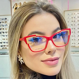 Detail of red and cream cat-eye glasses frame with model specs on the lens